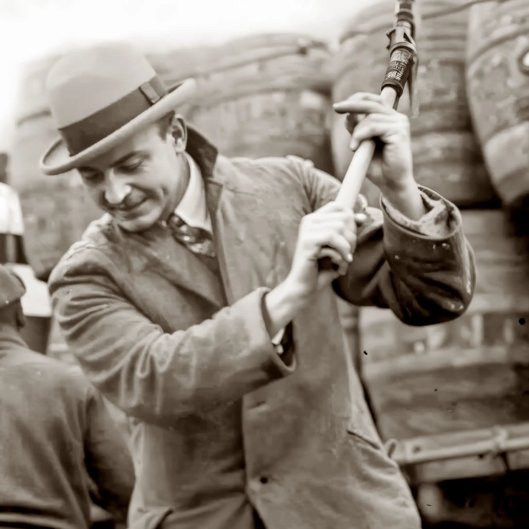 Close-up detail of federal agent with axe destroying prohibition liquor barrel showing enforcement determination