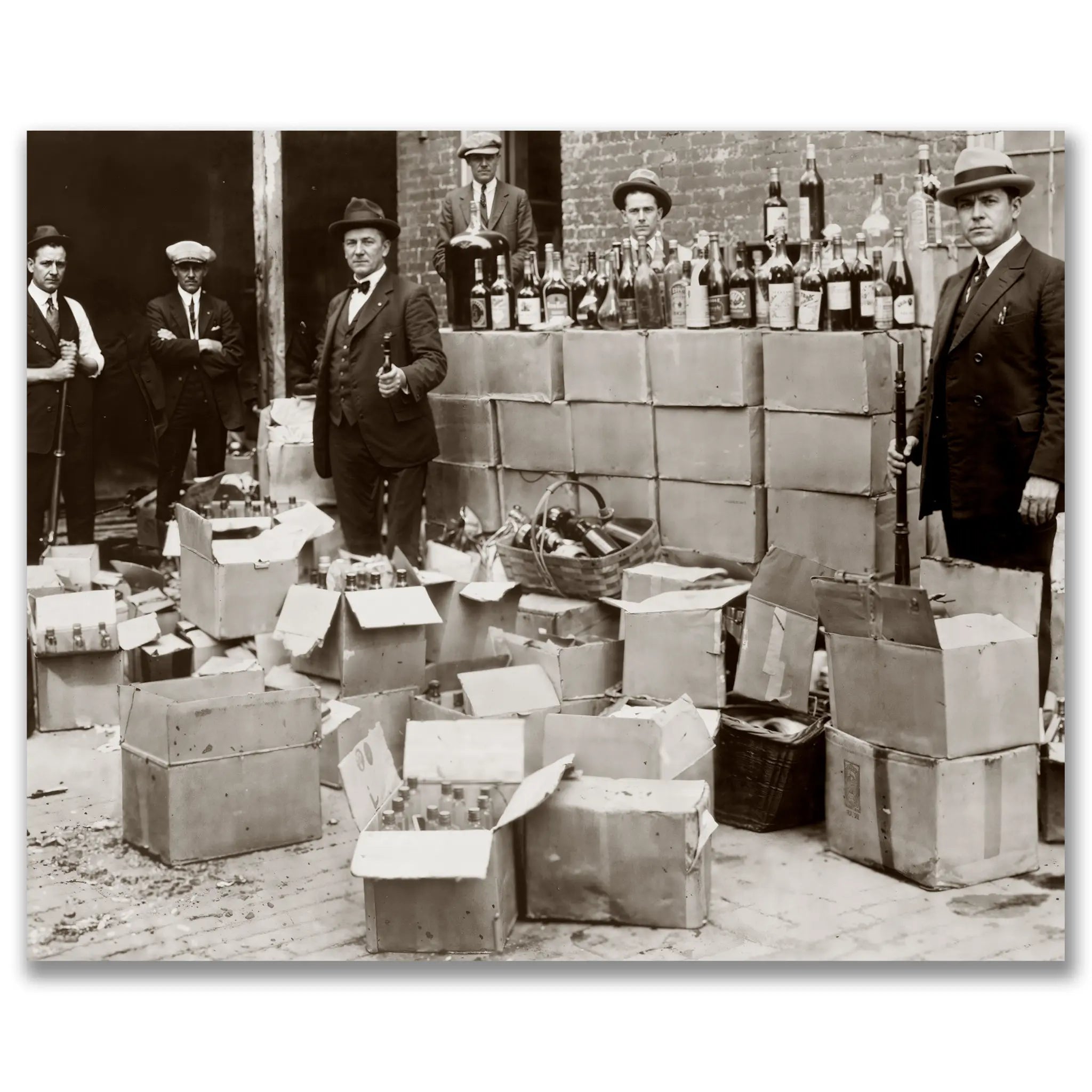 Historic prohibition era photograph showing federal agents with massive liquor seizure displaying hundreds of confiscated bottles and broken cases
