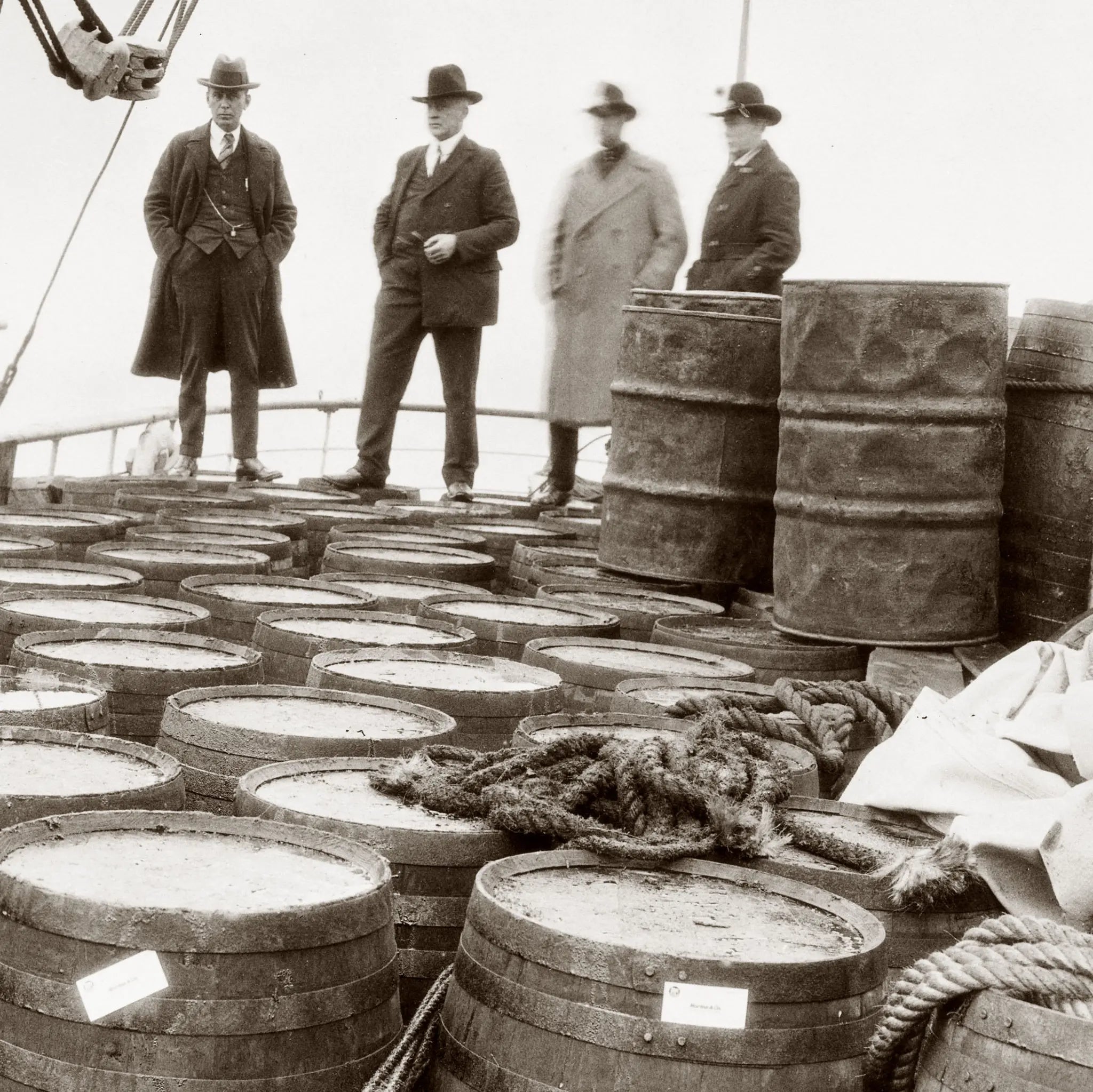 Close-up detail of prohibition liquor seizure showing federal agents and confiscated barrel arrangement on ship